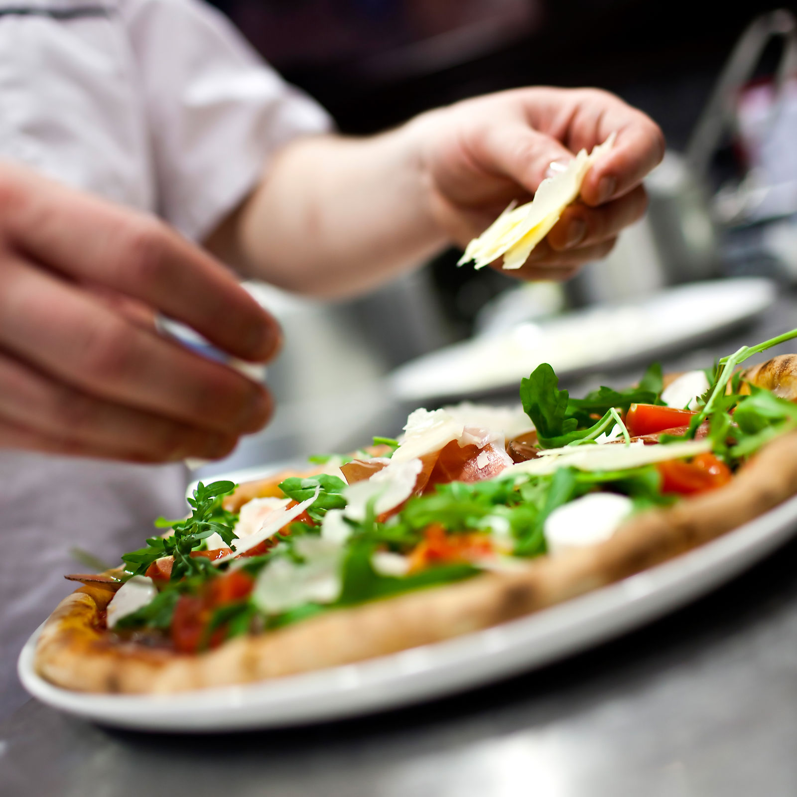 Closeup hand of chef baker in white uniform making pizza at kitchen.jpg